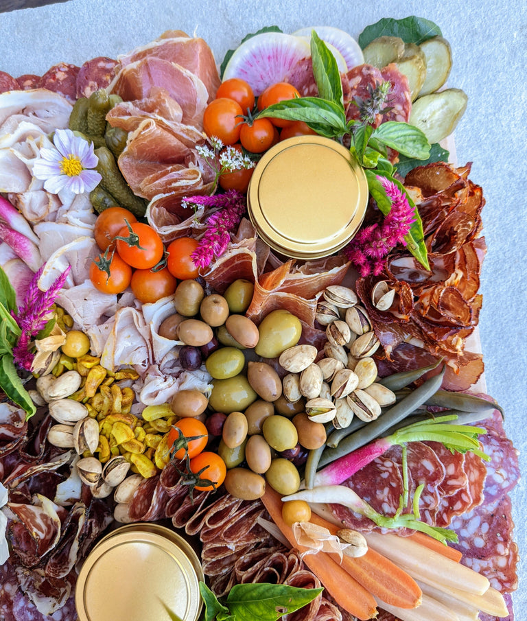 Cured meat charcuterie board with meats, pickles, olives, and nuts.